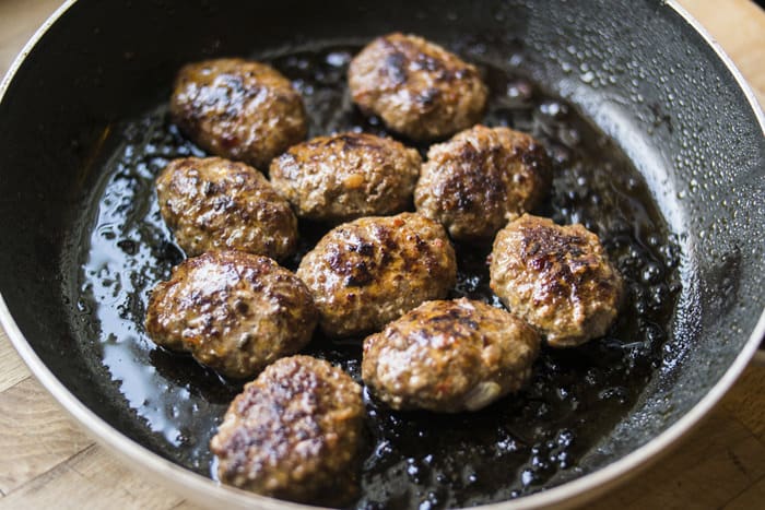 Meatballs are frying in a pan.