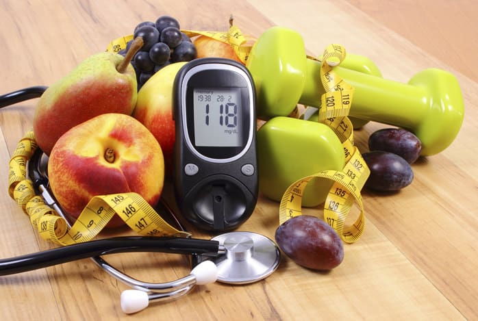 Glucose meter with medical stethoscope, fruits and dumbbells for using in fitness, concept of diabetes, healthy lifestyles and nutrition