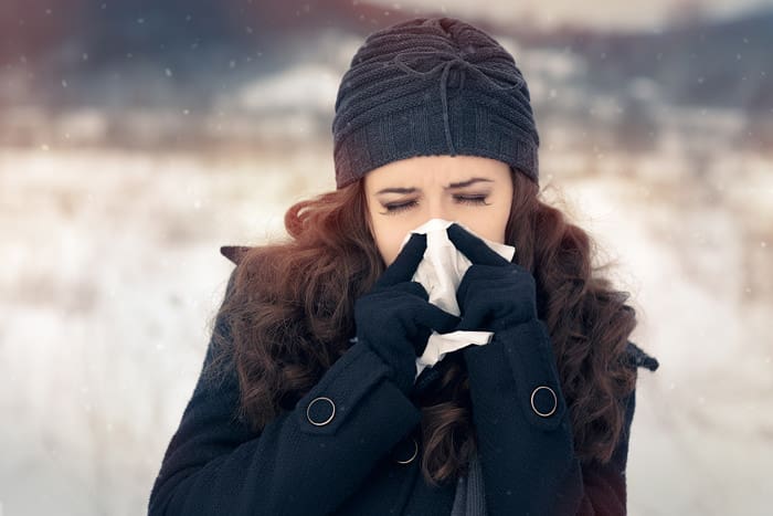 Suffering ill girl with flue being cold holding paper napkin in wintertime