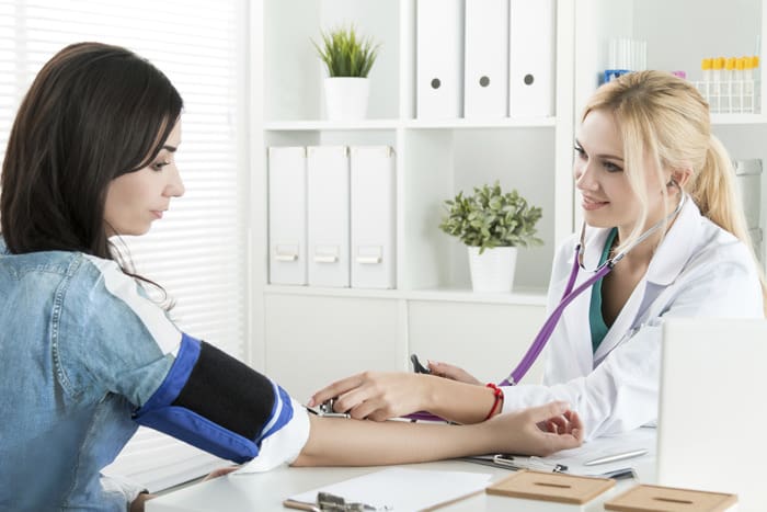 Beautiful smiling cheerful female medicine doctor measuring blood pressure to patient. Medical and healthcare concept