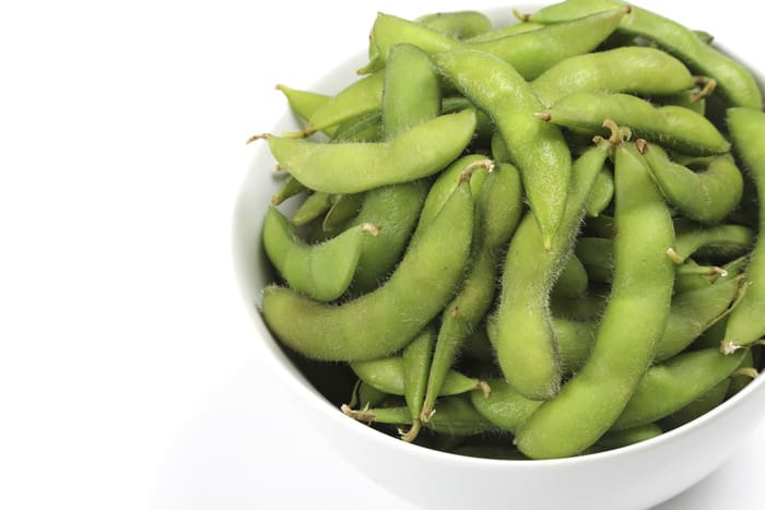 Whole edamame pods (green soybeans), cooked and ready to eat.