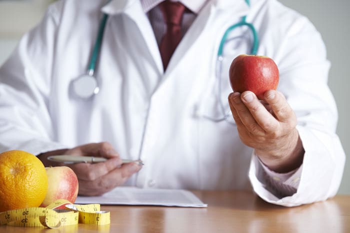 Arzt hält Apfel in der Hand